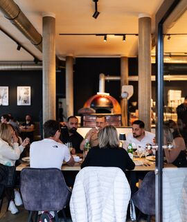 Blick durch die geöffnete Eingangstür in ein gut besuchtes Restaurant. Mehrere Personen sitzen an einem Tisch und essen gemeinsam bei einer Firmenfeier des Werksartrzentrums Deutschland.