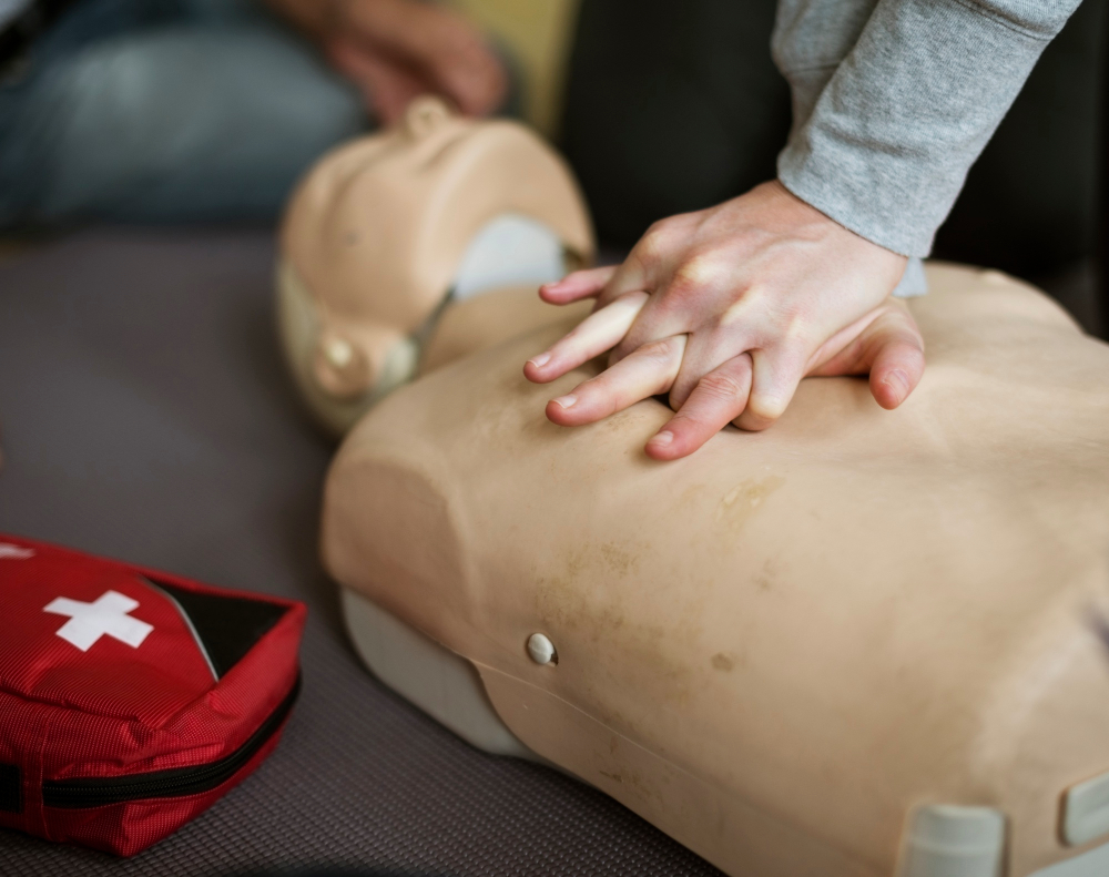 Eine Nahaufnahme von zwei Händen, die in einem Erste-Hilfe-Kurs Wiederbelebungsmaßnahmen an einem Dummy üben.