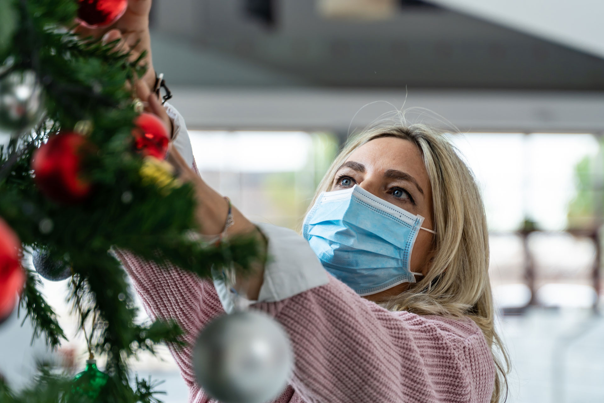 Ein Tisch auf dem mehrere Gesichtsmasken zum Gesundheitsschutz liegen. Im Hintergrund steht ein Weihnachtsbaum mit Lichterkette.