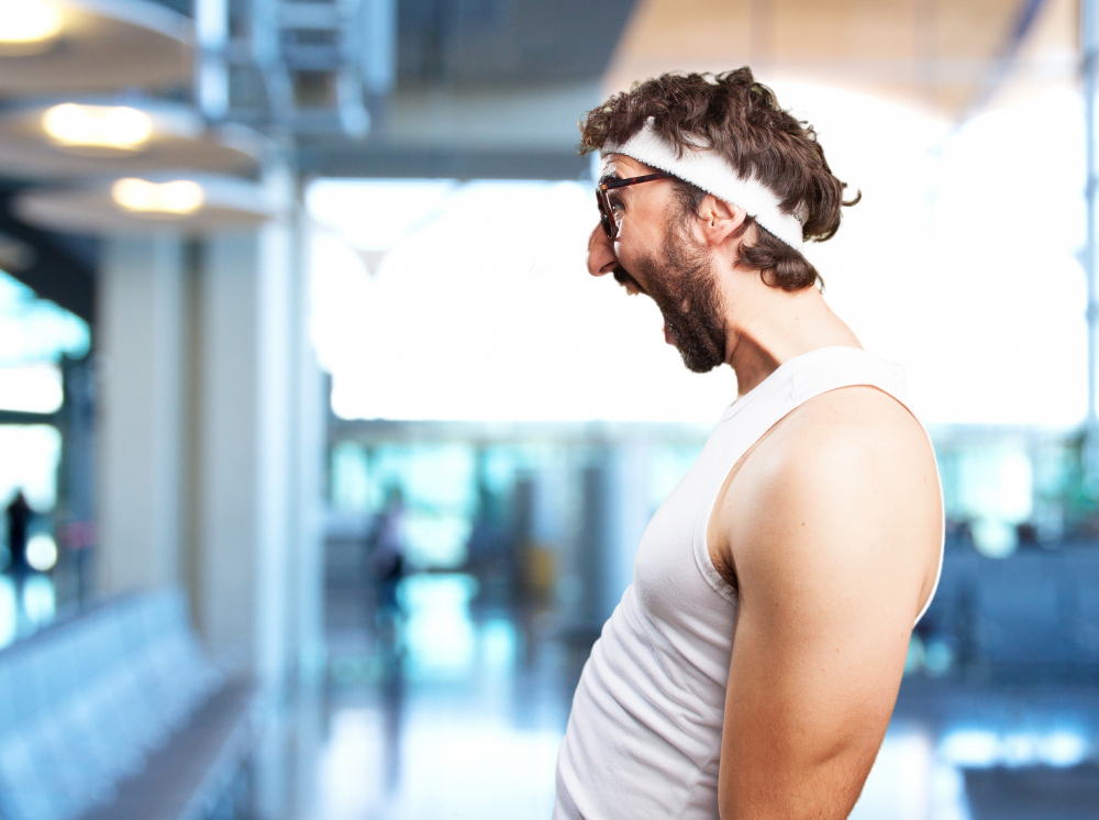 Stefanue sitzt an ihrem Arbeitsplatz. Links sehen wir eine Fensterbank mit Pflanzen. Sie selbst ist in der Mitte des Fotos mit einem blauen Oberteil und einer Brille.